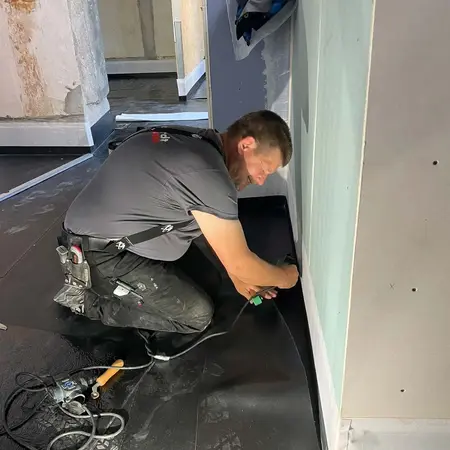 Handwerker verlegt professionell Bodenbelag und nutzt Werkzeug zur Bodenverarbeitung.